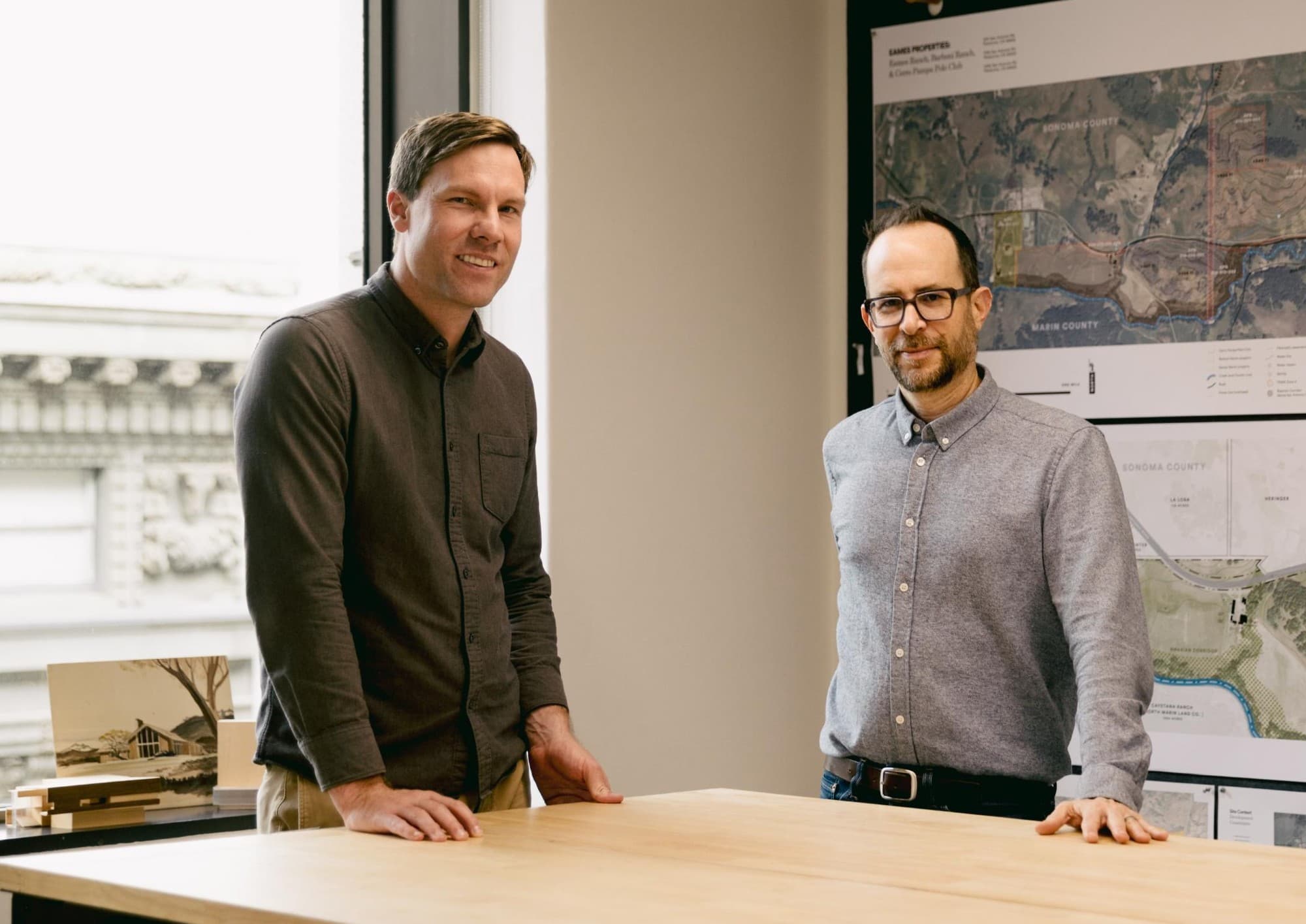 C.Scale co-founders Jack Rusk and Brad Jacobson standing at a table in front of site plans
